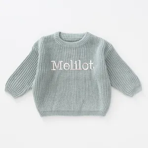 Close-up of chunky blue knit girl's pullover sweater featuring Melilot name embroidery