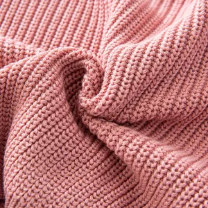 Macro detail shot showing the soft pink ribbed knit texture of a cozy girl's sweater