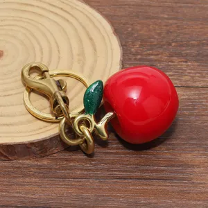 Primo piano di un portachiavi a forma di mela rossa lucida su base di legno