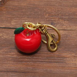 Dettaglio di un portachiavi a forma di mela rossa lucida con robusta chiusura dorata