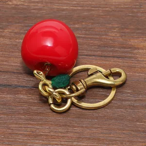 Primo piano di un portachiavi a mela rossa con una chiusura a moschettone dorata