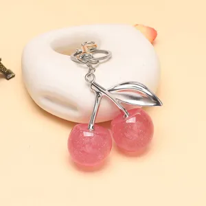 Détail d'un porte-clés cerise rose scintillant avec une tige et une feuille argentées