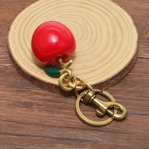 Dettaglio di un portachiavi a mela rossa lucida con gancio in ottone stile vintage