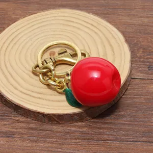 Dettaglio di un portachiavi a forma di mela rossa con foglia verde su legno