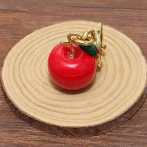 Primo piano di un portachiavi a forma di mela rossa lucida con finiture color oro