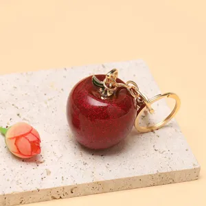 Primo piano di un portachiavi a forma di mela rossa glitterata su base in pietra