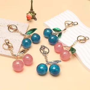 Détail de porte-clés cerises scintillants roses et bleus avec attaches dorées