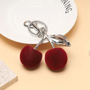 Vue détaillée d'un porte-clés cerise en velours rouge avec tige et feuille en métal argenté
