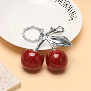 Gros plan d'un porte-clés cerise rouge à paillettes avec des accessoires argentés.