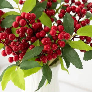 Gros plan de baies rouges artificielles et feuilles vertes branche de décoration.