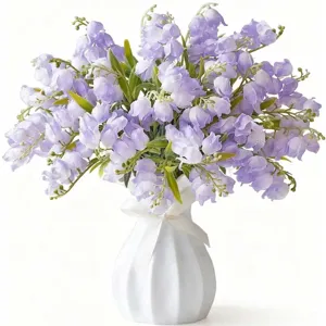 Gros plan détail de bouquet de muguet violet artificiel dans un vase en céramique blanche.