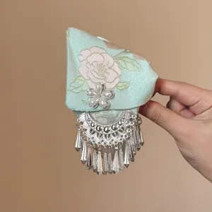 Pinza de pelo verde menta estilo chino con patrón floral y borlas plateadas colgantes.