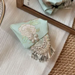 Pinza de pelo china verde menta bordada con perlas y borlas plateadas en detalle.
