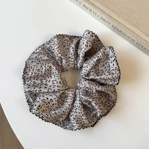 Primer plano de un elegante coletero de satén con estampado abstracto y borde negro.