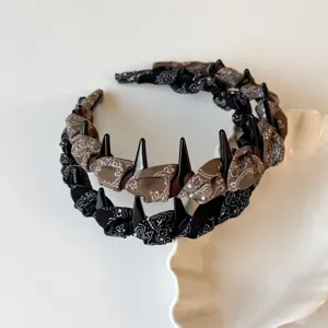 Detailed close-up shot of pleated patterned teeth headbands in brown and black styles.