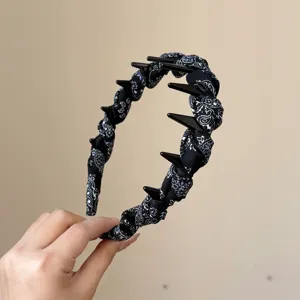 Close-up detail of pleated fabric hairband with teeth and black paisley print for stylish wear.