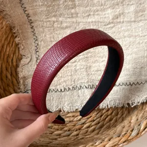 Closeup of a burgundy crocodile pattern wide padded headband, vintage retro hair hoop detail.