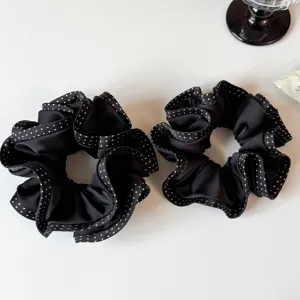 Detailansicht von zwei schwarzen Rüschen-Haargummis mit feinen weißen Polka-Dot-Kanten