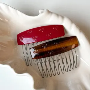 Primo piano di due pettini per capelli in acetato con motivi a fiocco in tonalità rosso e marrone.