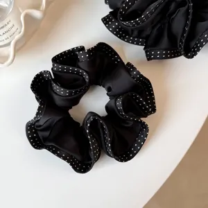 Detailansicht eines schwarzen Haargummis mit eleganten weiß gepunkteten Rüschenkanten