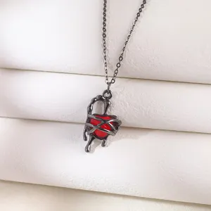 Close-up of gothic red heart pendant necklace with black melting metal thorns