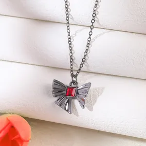 Detailed view of gothic bow necklace with rectangular red gemstone and black chain.