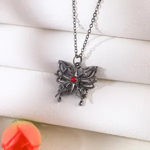 Macro detail showing gothic style black metal butterfly pendant with a red gemstone