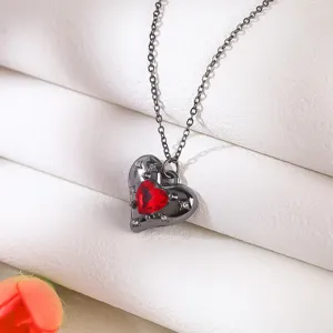 Macro view of gothic black heart necklace with a red gem and star engraving details