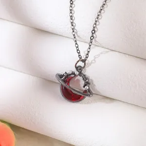 Close-up detail of a gothic necklace featuring a red crescent moon and planet stars.