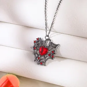 Macro detail of a gothic spider web necklace featuring a vibrant red heart gemstone.
