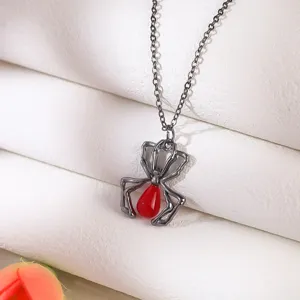 Macro detail of a gothic spider pendant featuring a glossy red teardrop stone accessory
