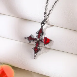 Detailed macro of a Gothic cross necklace with a red heart gem on white fabric.