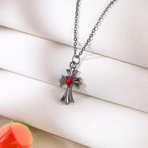 Detailed close-up of a gothic black cross necklace featuring a vibrant red heart gem center.