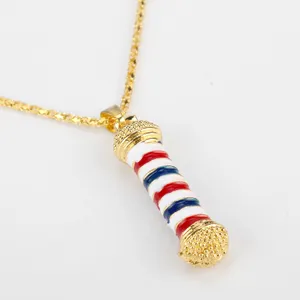Primo piano di una collana dorata con ciondolo smaltato a forma di palo da barbiere tricolore