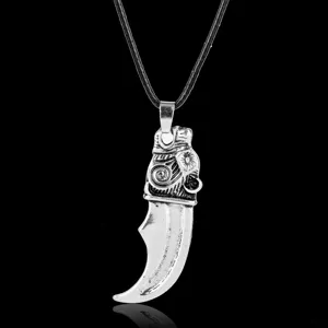 Macro view of Viking wolf tooth pendant with intricate vintage silver carvings on black