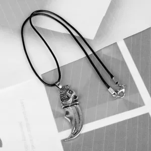 Close-up detail of a silver-toned Viking wolf claw pendant with intricate Norse carvings