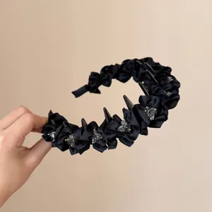 Zwarte stoffen golvende haarband met tanden en sprankelende kristallen, haaraccessoire detail.