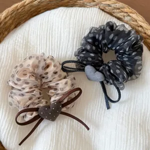 Vue detaillee de chouchous a pois en organza avec joli ruban et pendentif coeur pour coiffure.