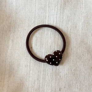 Detailed shot of a dark brown hair tie with a glossy polka dot heart ornament for daily use.