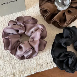 Detail shot of satin hair scrunchies with multi-layer ruffled edges, elegant and silky texture.