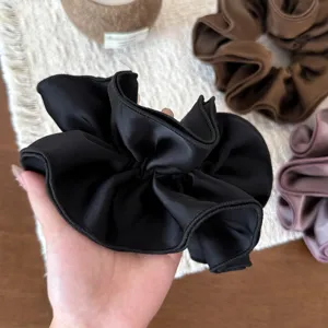Black satin hair scrunchie with multi-layer ruffled edge, exquisite close-up presentation.