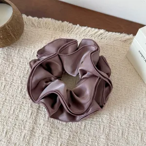 Detailed shot of a luxurious dark mauve satin hair scrunchie with layered ruffles.