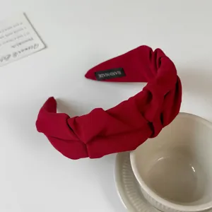 Close-up detail of the wine red pleated wide headband, fabric hair hoop with handmade label.