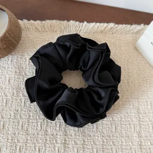 Detailed close-up view of the elegant black satin ruffled hair scrunchie displaying soft texture.
