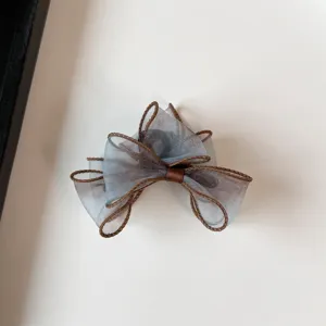 Close-up of the gradient organza bow hair claw, showing exquisite brown stitched edges.