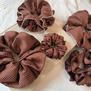 Brown polka dot hair scrunchies detail, ruffled pleats elastic hair tie close up view.