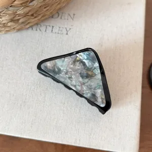 Primo piano dettagliato della pinza per capelli triangolare elegante con acetato perlato.