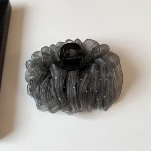 Detailed close-up of a sparkling black mesh hair claw clip with silver star rhinestones.