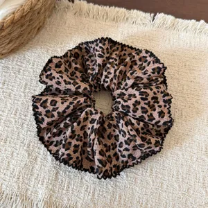 Detalle de un coletero grande con estampado de leopardo retro y borde negro voluminoso.