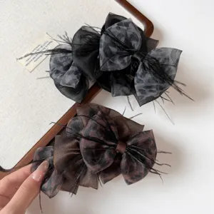 Close-up detail of Korean leopard print mesh bow hair claw clip with stylish feathers.